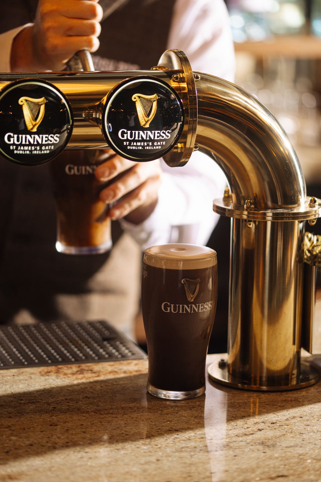 A bartender is pouring guinness beer into a glass