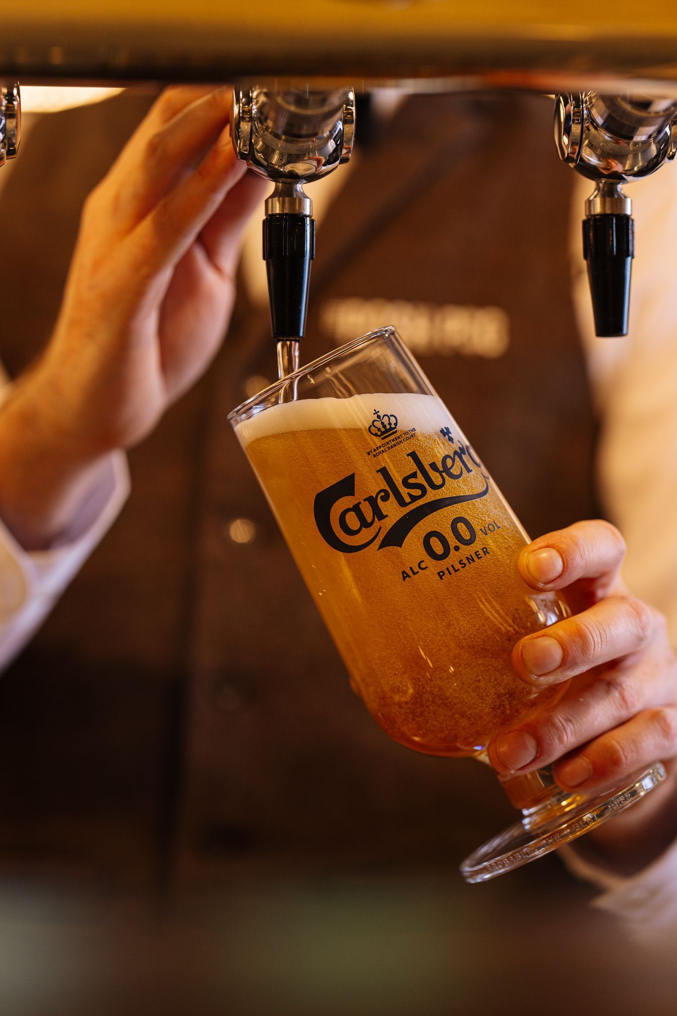 A person is pouring carlsberg beer into a glass