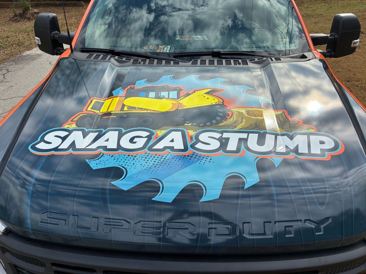 Tree surgeon in green cutting a tree branch with a chainsaw, harnessed, outdoors.