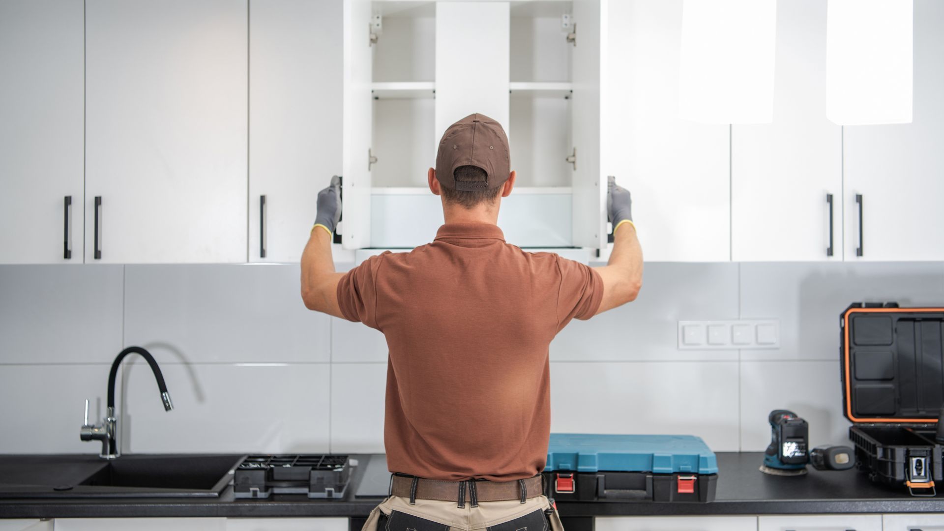 Man installing white kitchen cabinet.