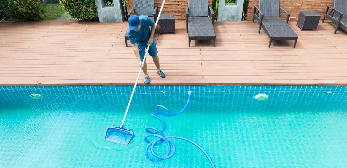 Person cleaning a swimming pool with a net.