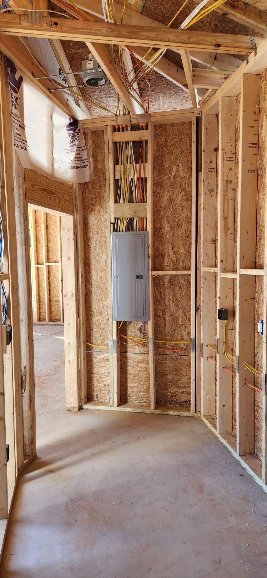 Interior of a building under construction, showing wooden frames and an electrical panel on the wall.