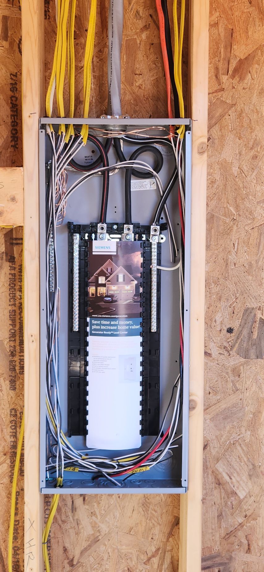 Electrical panel with wires and a brochure mounted in a wooden frame.