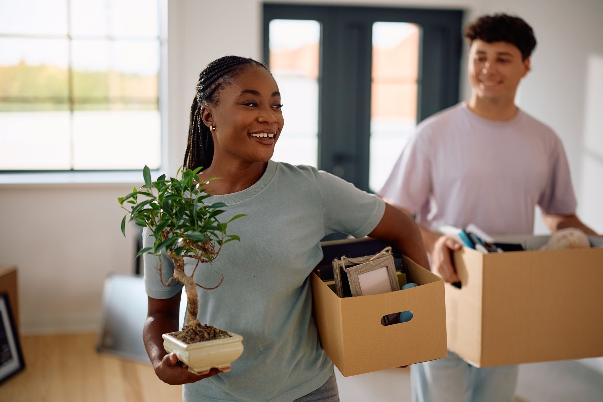 A man and a woman are carrying boxes into a new home.