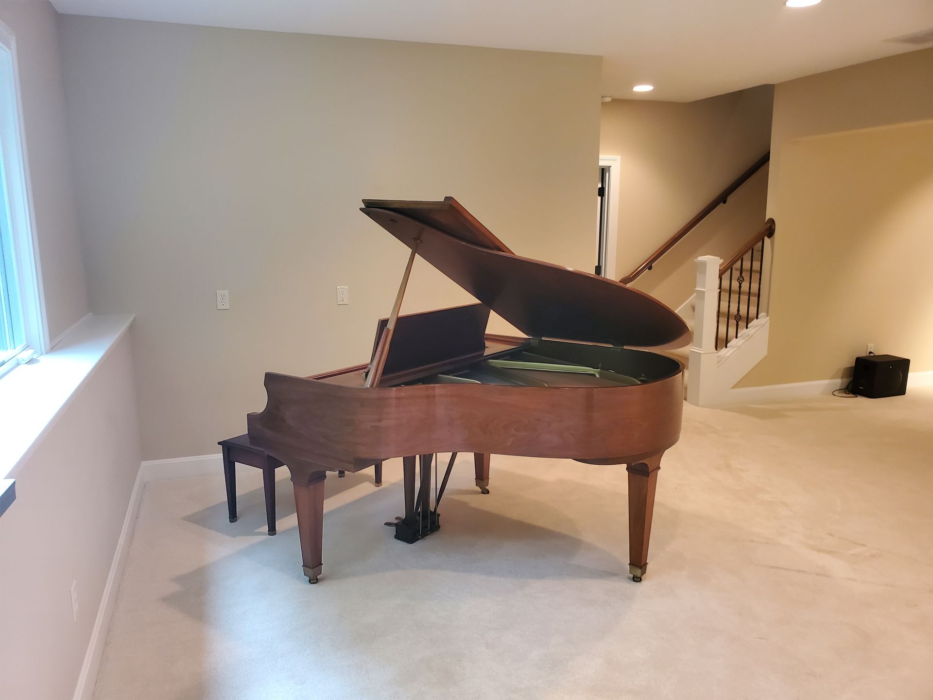 A piano is sitting in a room next to stairs