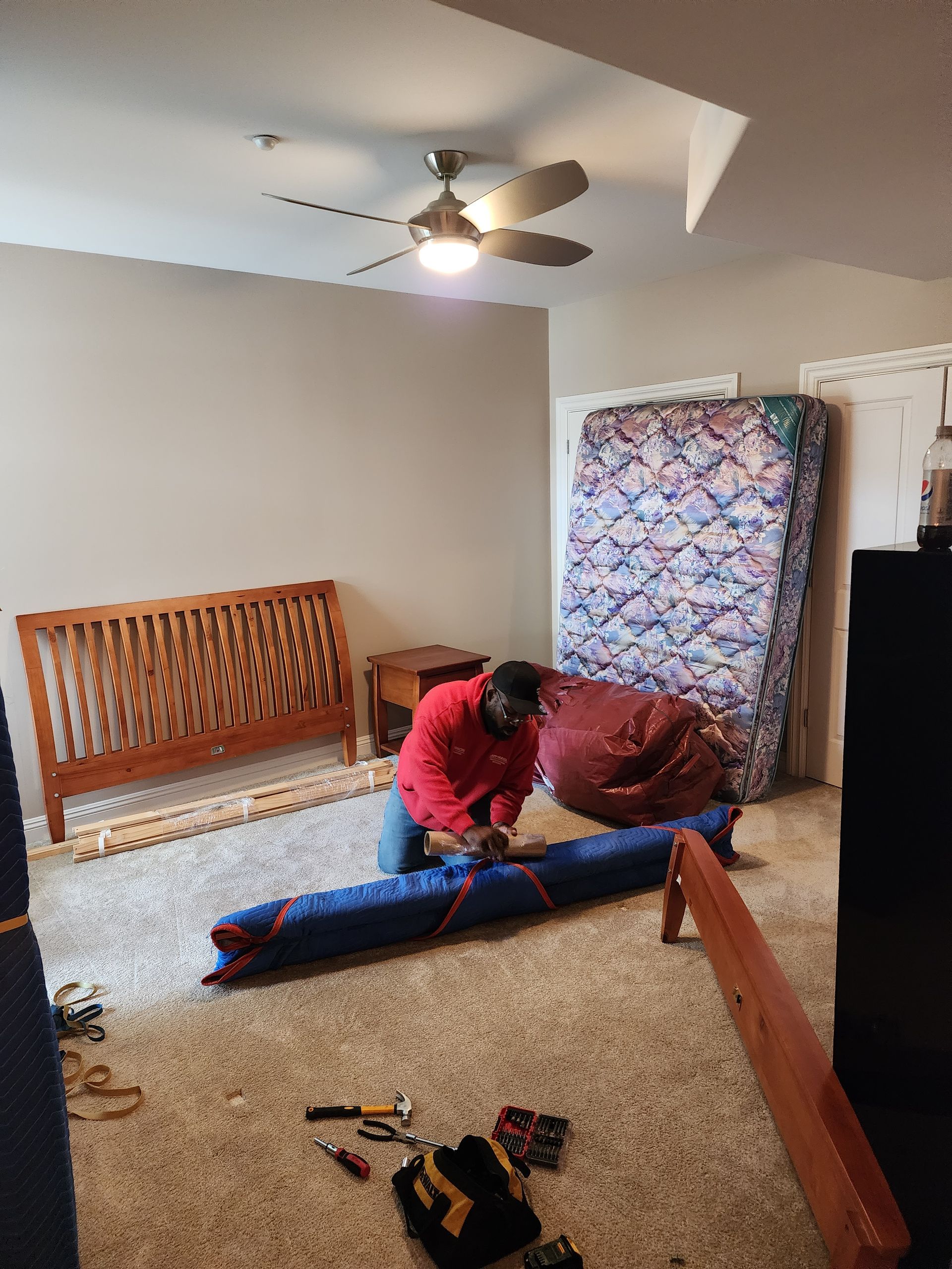 a man is kneeling down in a bedroom holding a mattress.