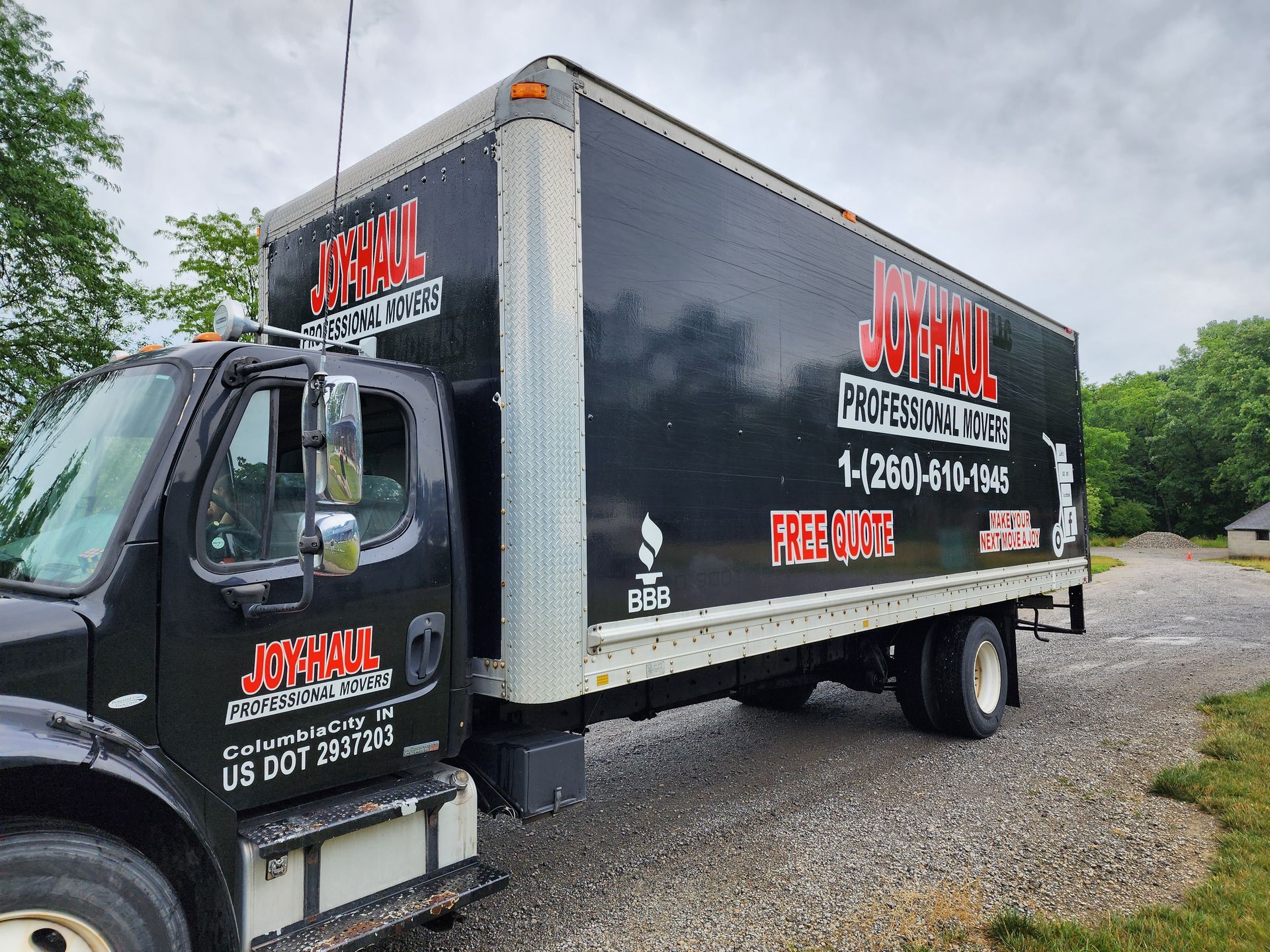 A black and white moving truck is parked in a gravel lot.