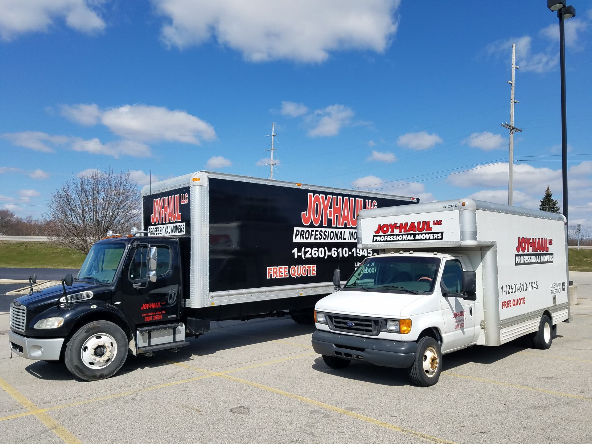 Two moving trucks are parked next to each other in a parking lot.