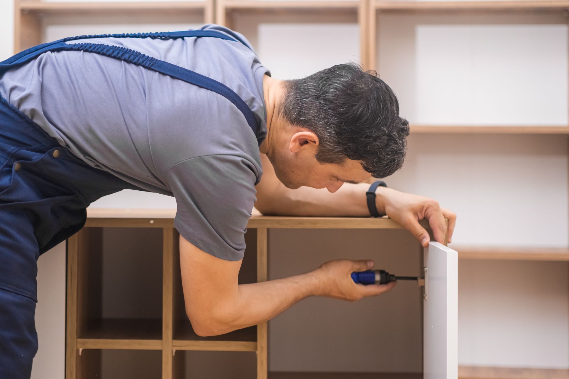 a man is working on a cabinet with a screwdriver