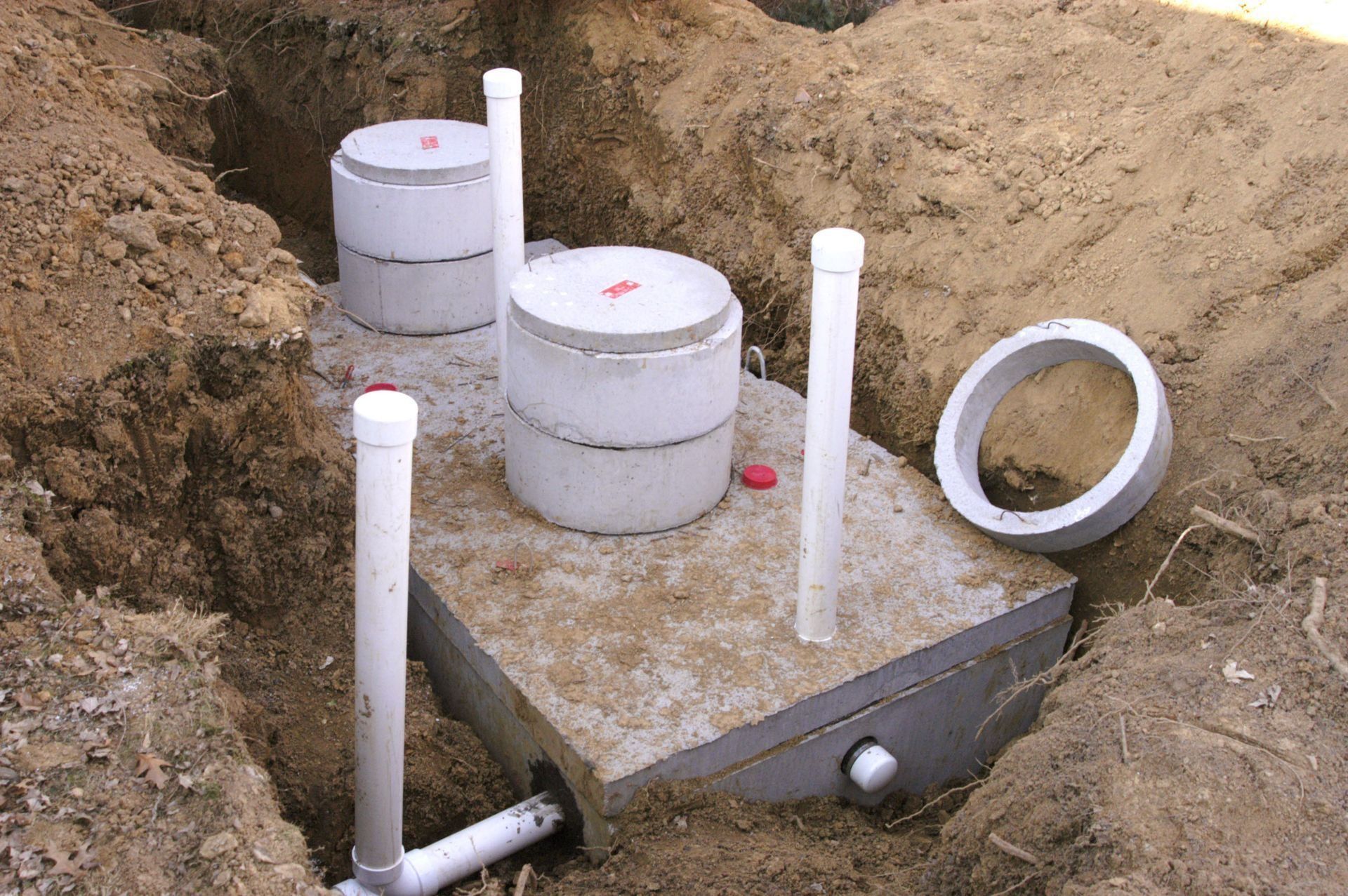 Installation of a septic system. Concrete tanks and pipes are set in a trench.