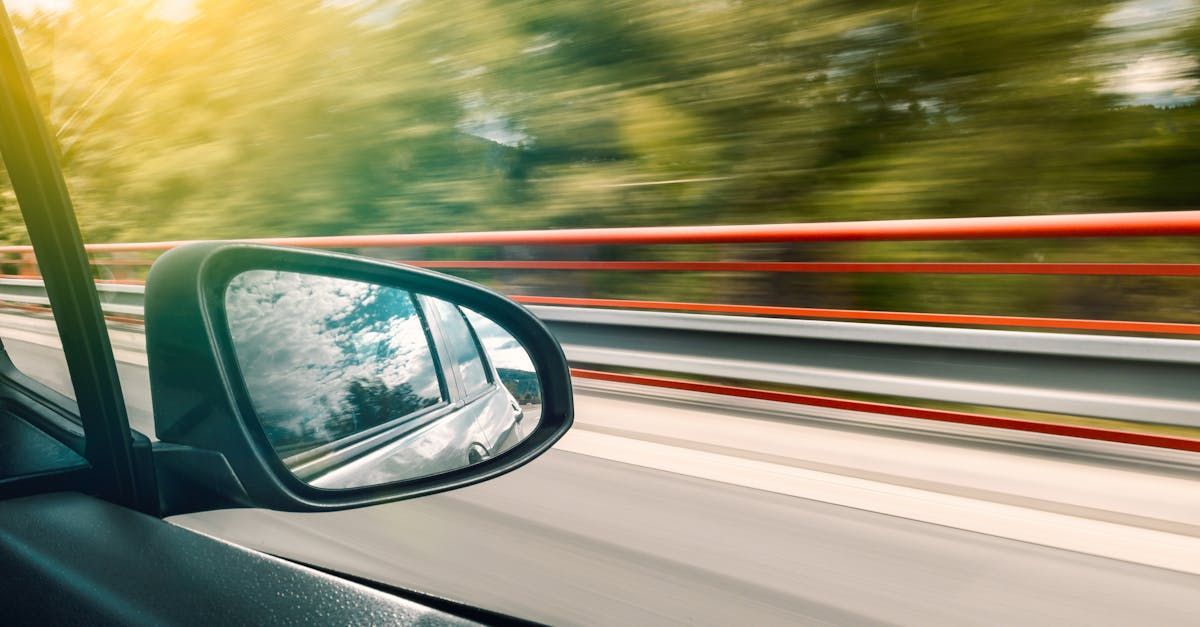 A car is driving down a highway and the rear view mirror is visible. | Browns Automotive