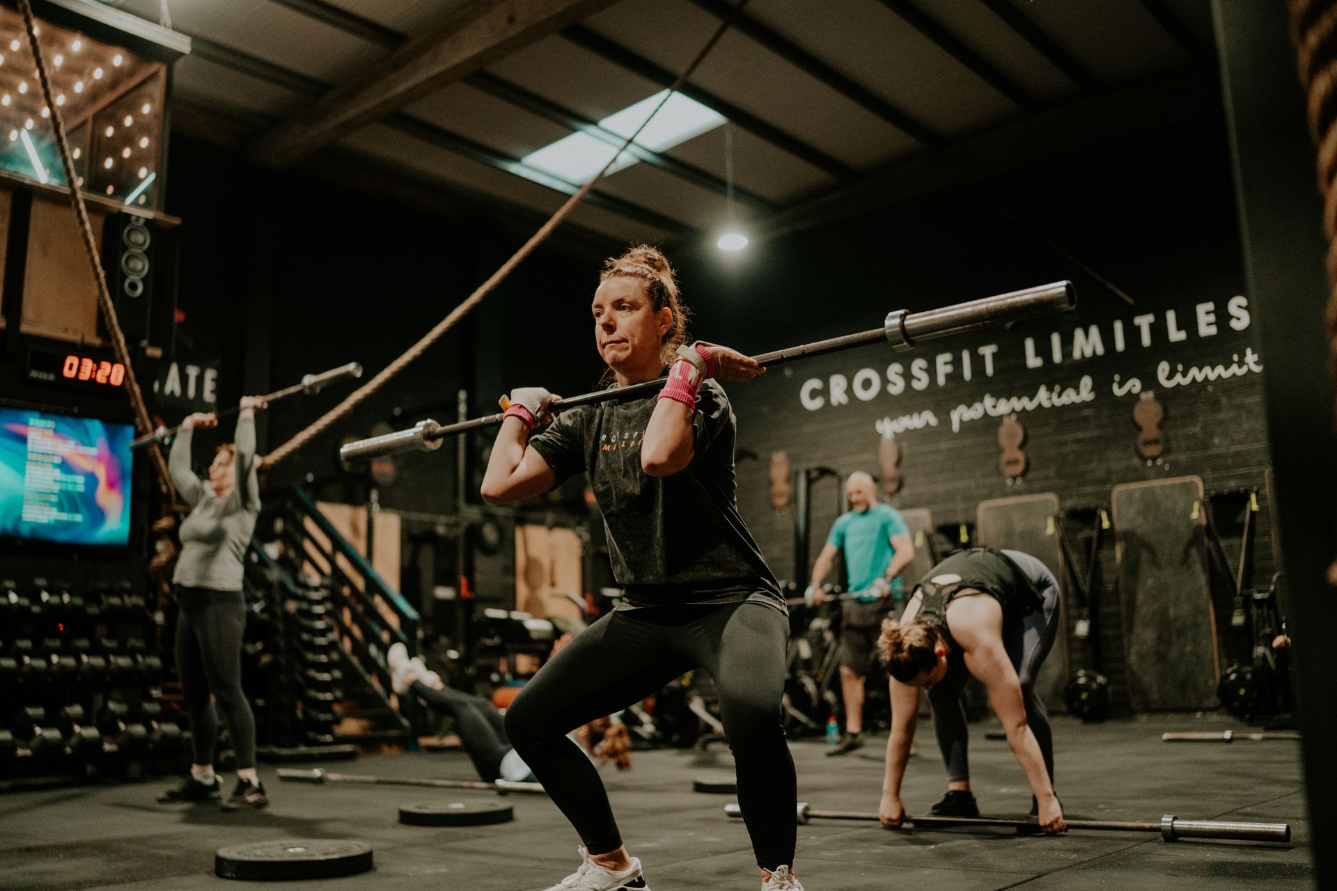 A woman is squatting with a barbell in a gym.