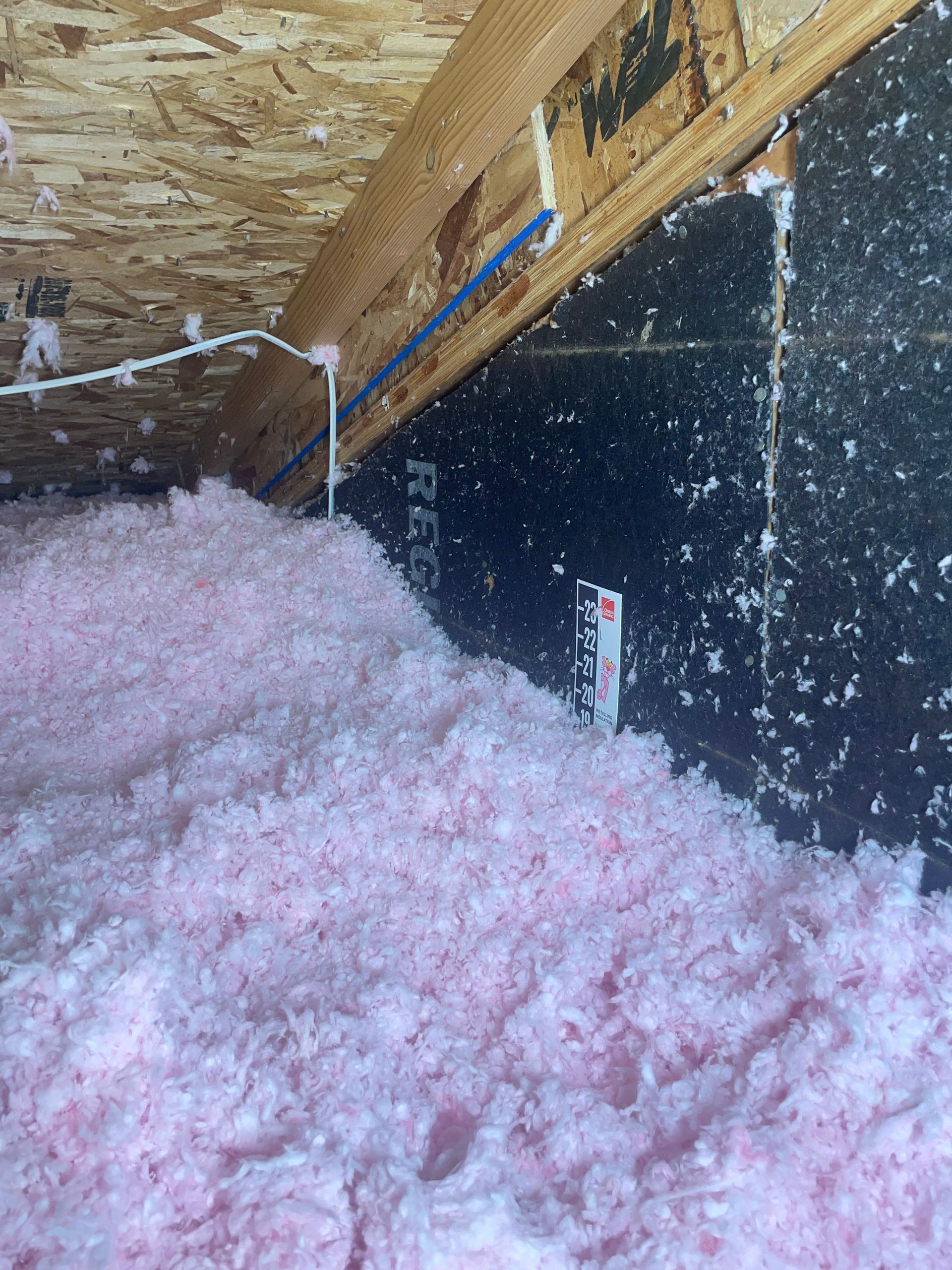 There is a lot of pink insulation in the attic of a house.
