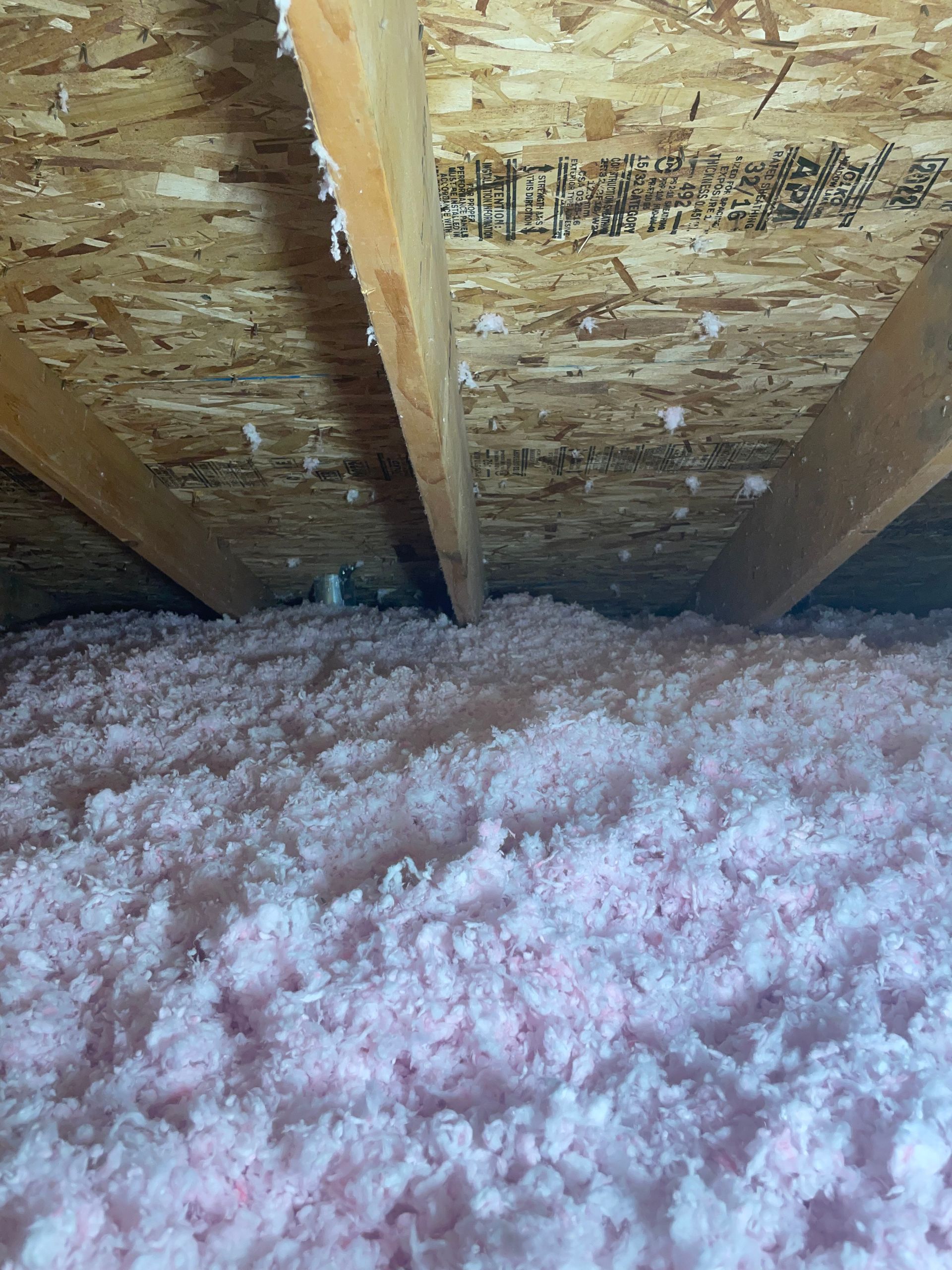 There is a lot of pink insulation in the attic of a house.