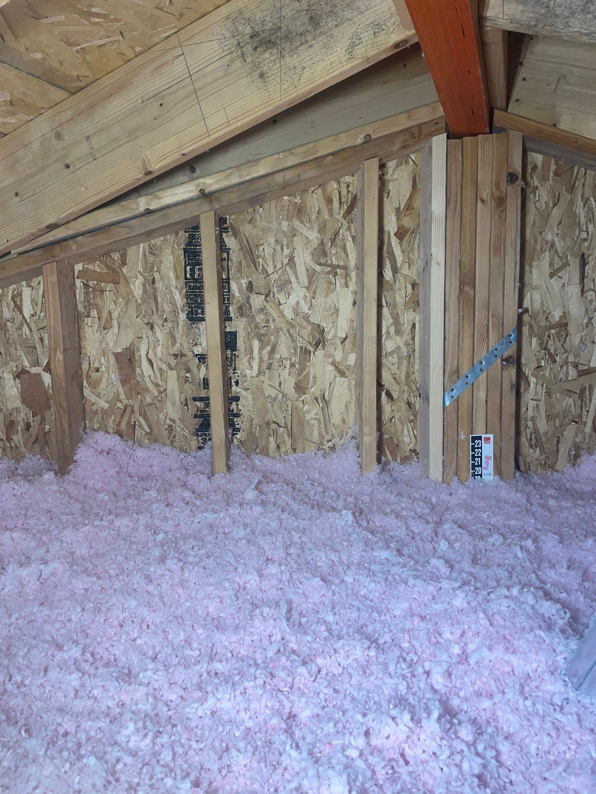 There is a lot of pink insulation in the attic of a house.