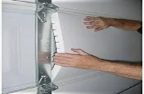 Two beige metal garage doors in an enclosed, concrete space.