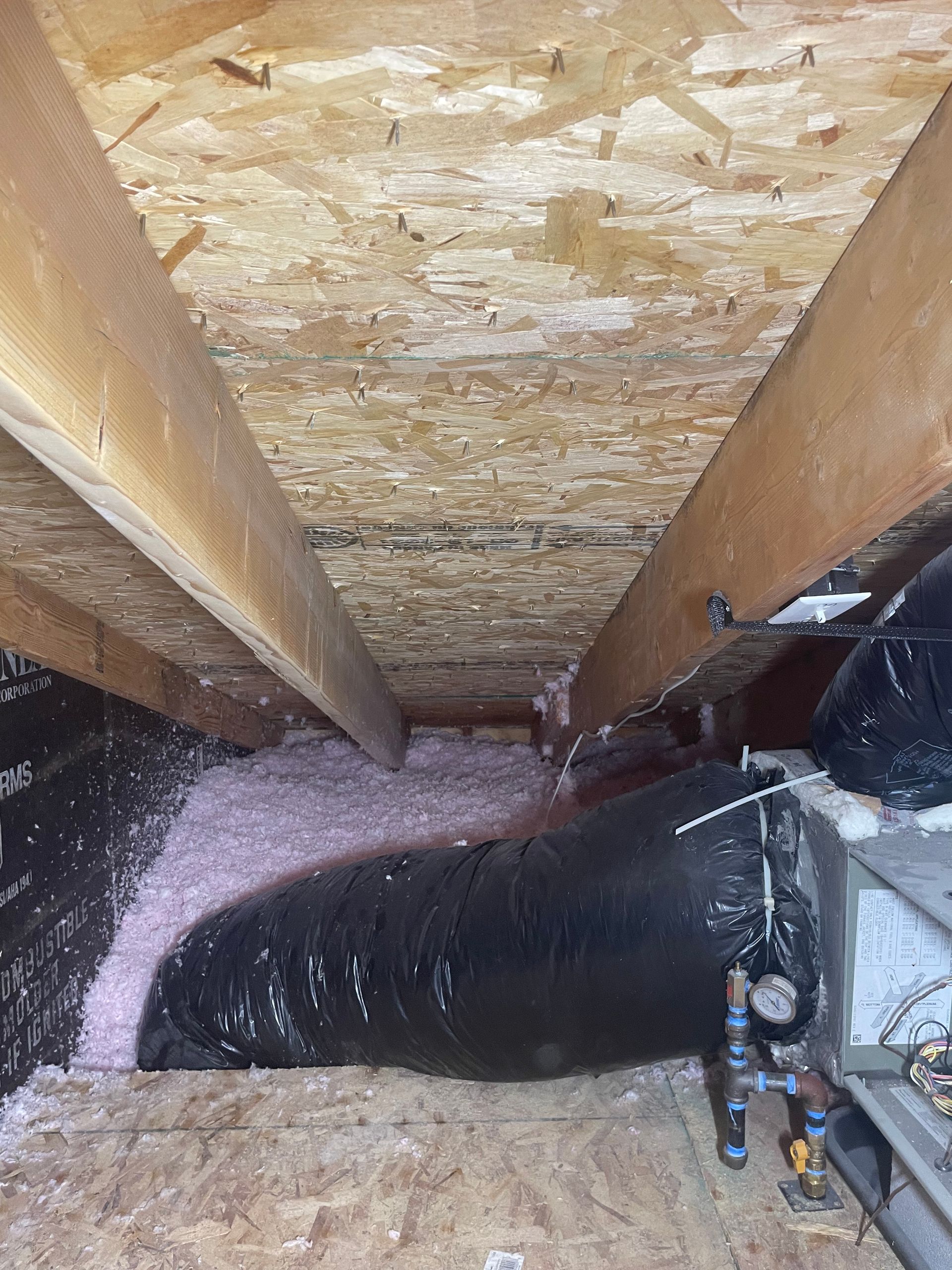 There is a large pipe in the attic of a house.