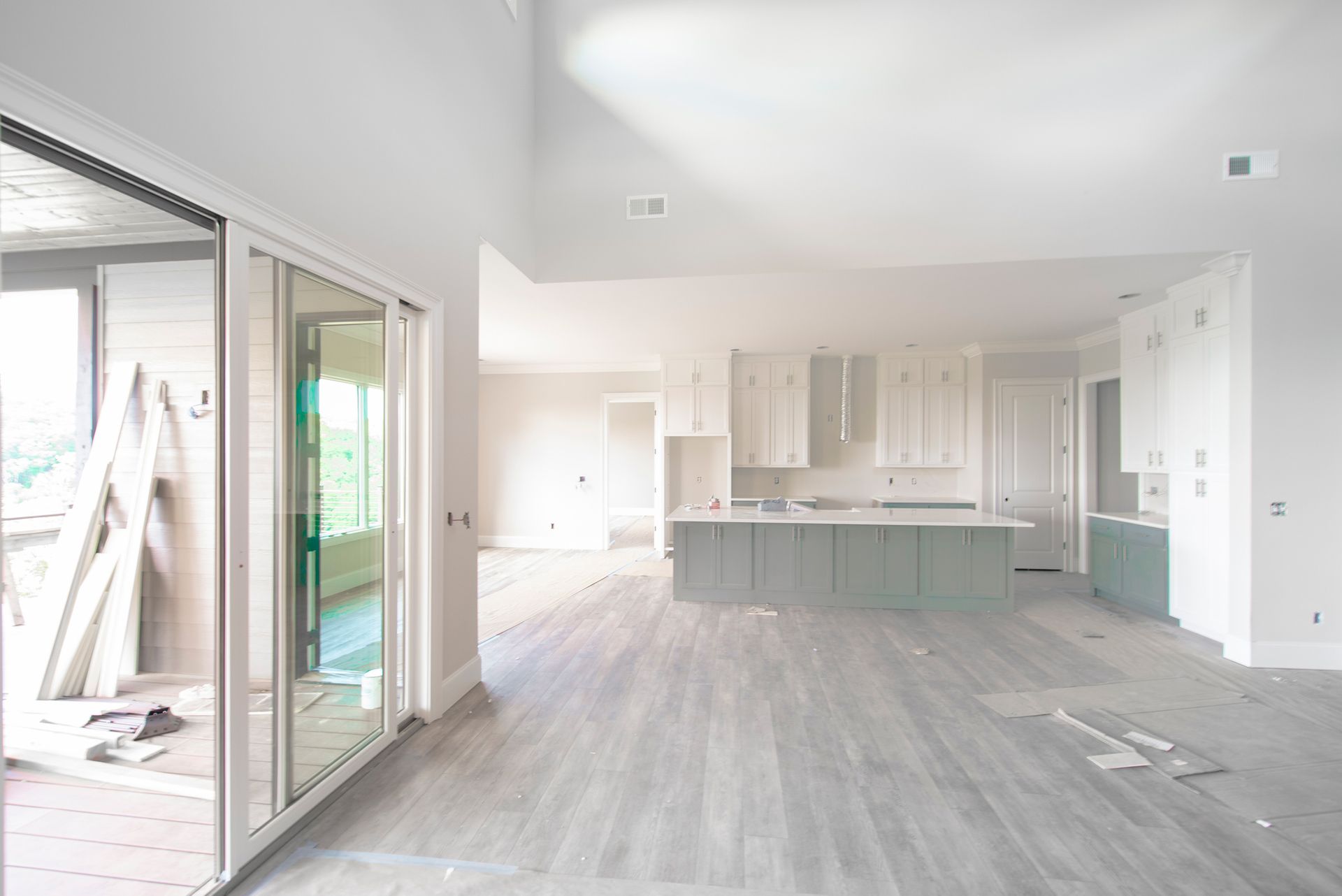 A large empty room with a kitchen and sliding glass doors.