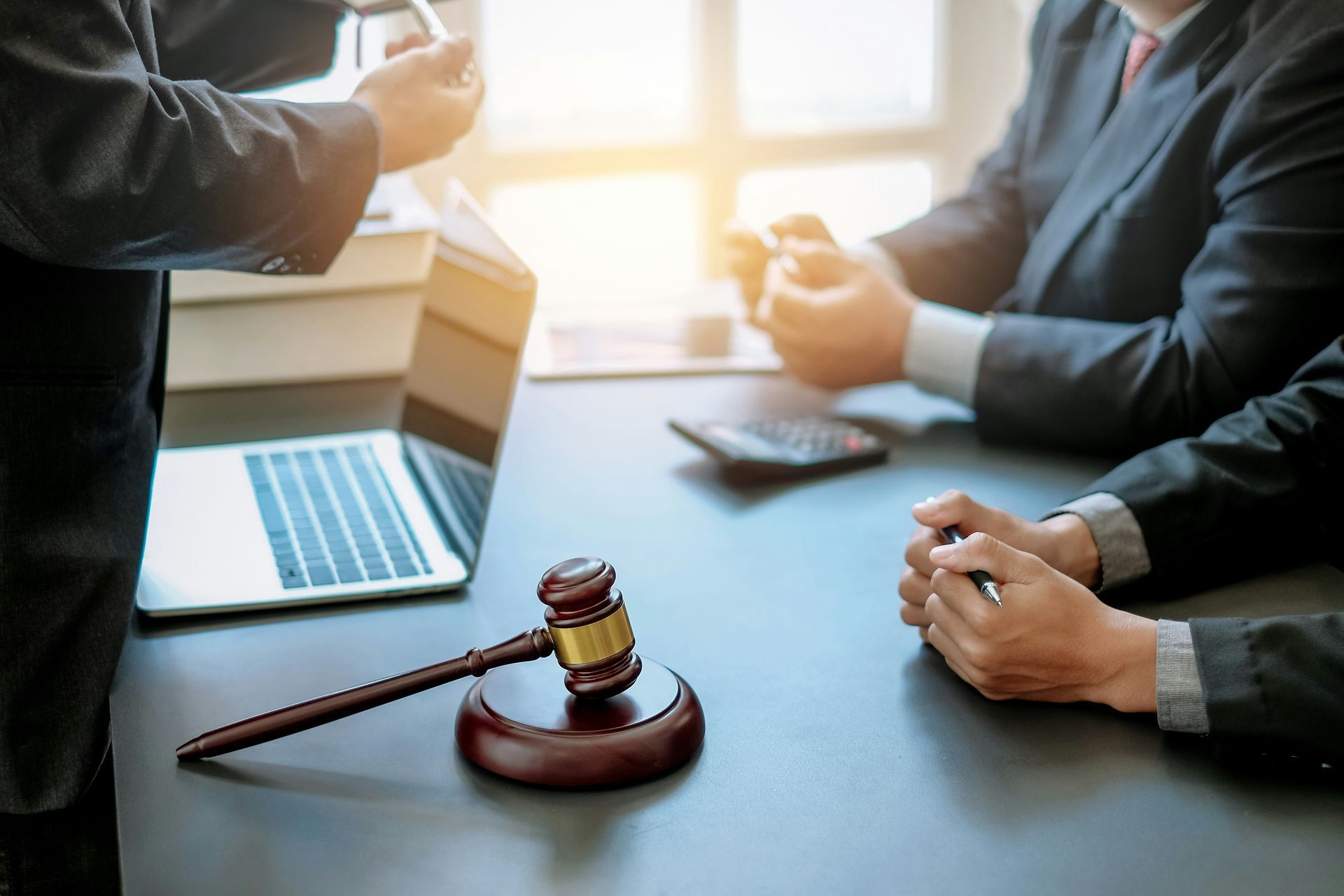 Lawyers in suits at a table with a gavel and laptop; discussing legal matters. 