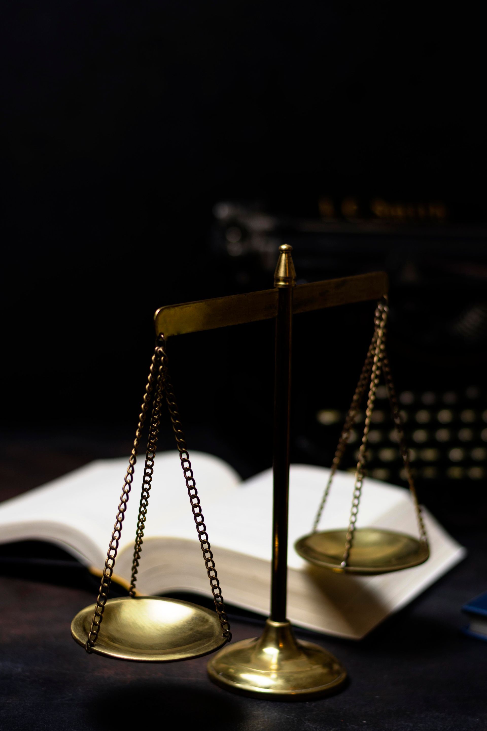 Scales of justice with a book and a typewriter in the background.