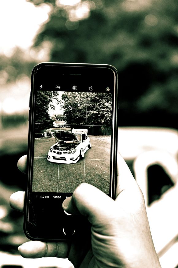 A person is taking a picture of a car with a cell phone