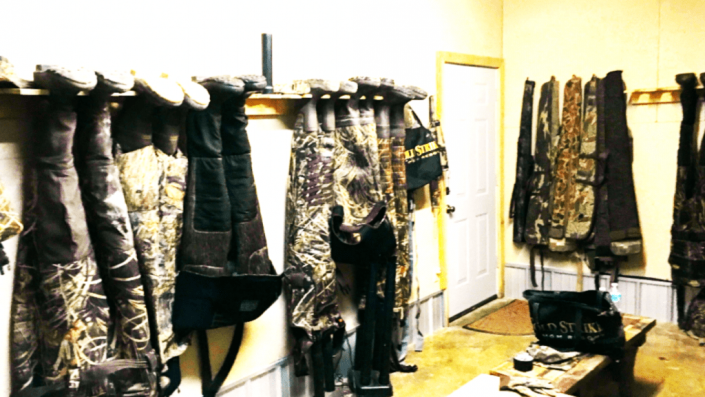 Rows of camouflage and black clothing hanging in a brightly lit shop or studio.