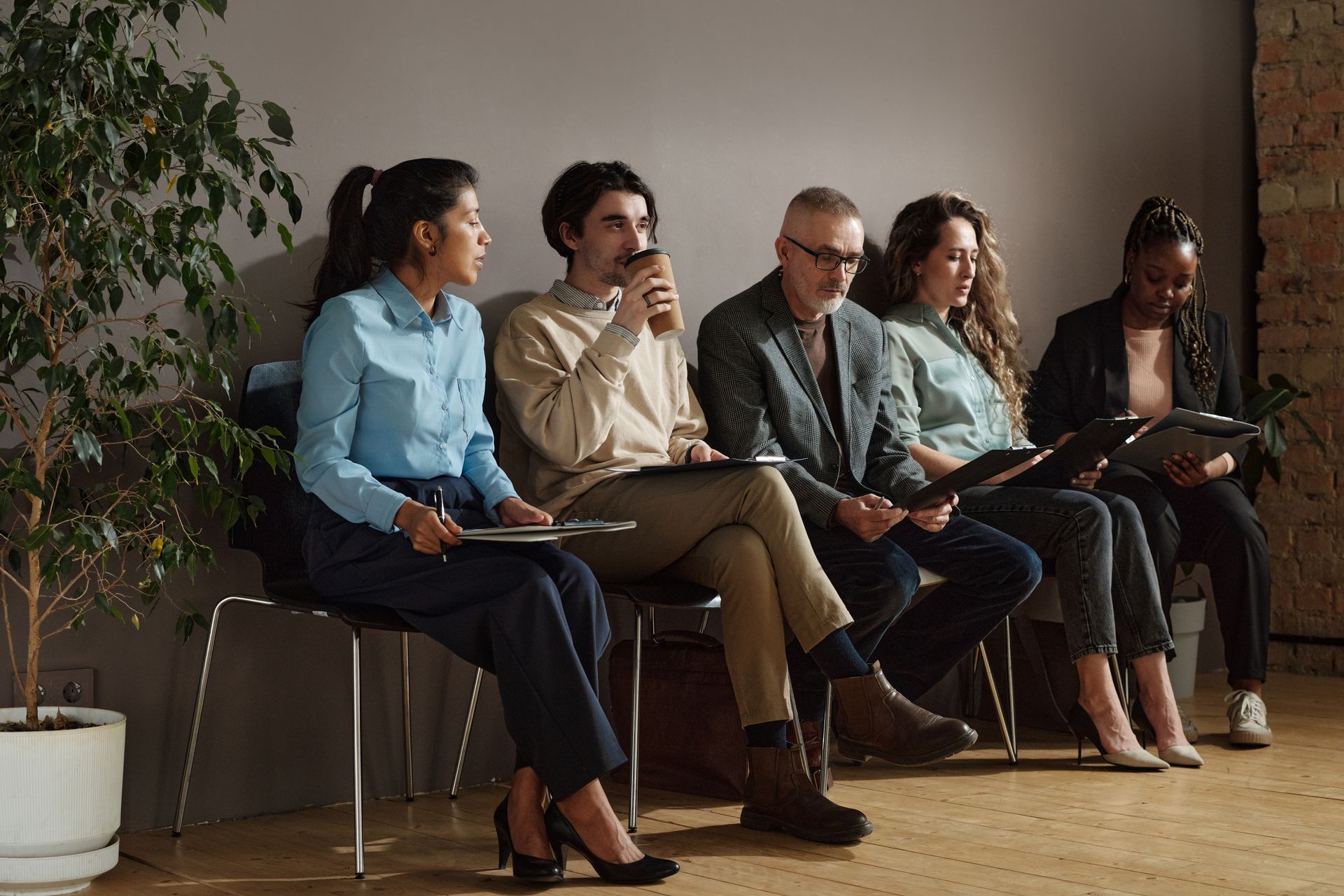 A group of people are sitting in chairs waiting for a job interview.