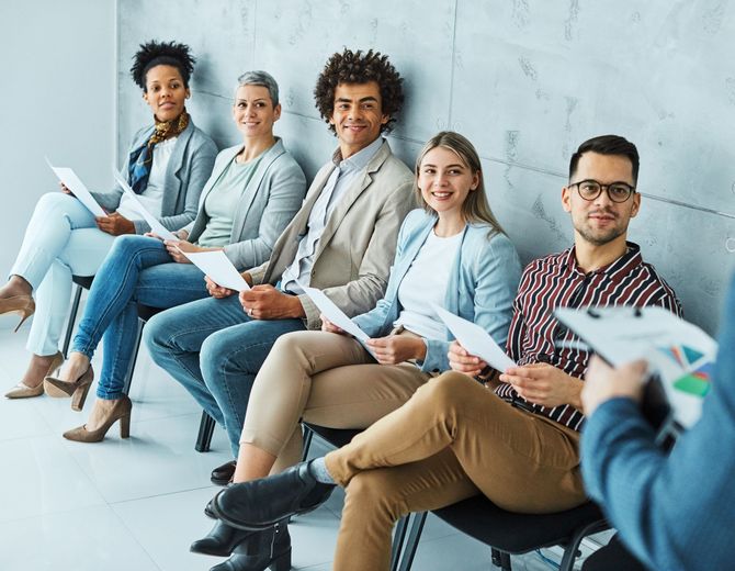 A group of people are sitting in chairs waiting for a job interview.