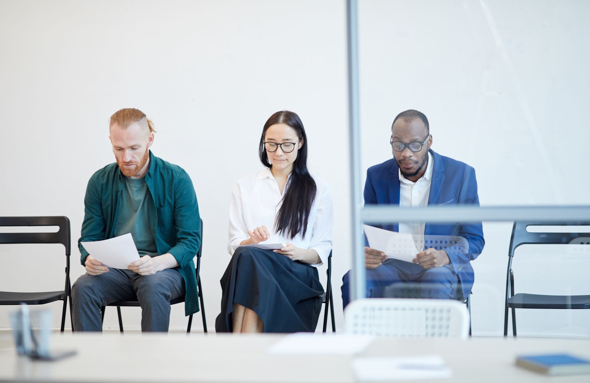 A group of people are sitting in chairs waiting for a job interview.