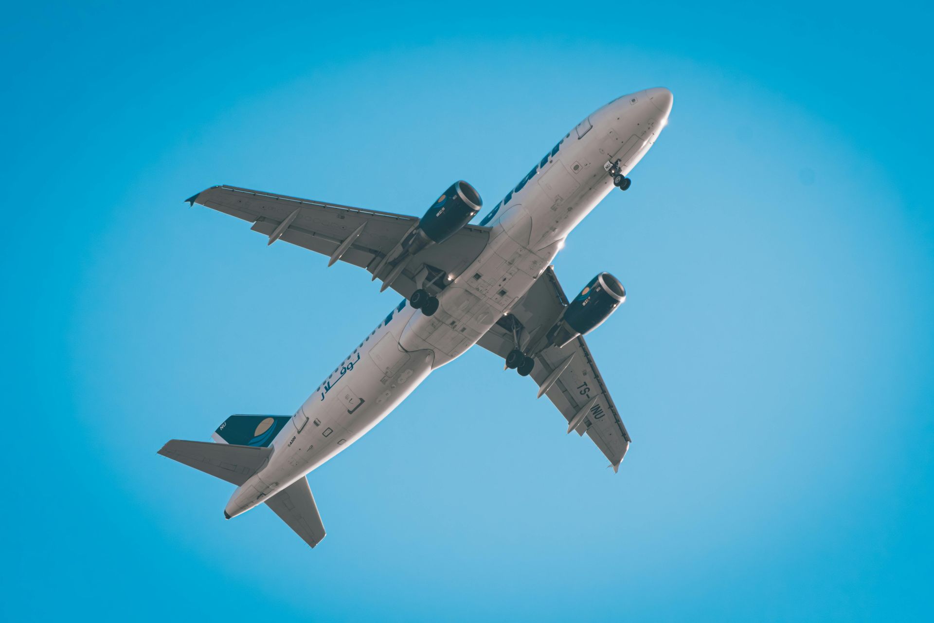 An airplane, white with blue accents, ascending into a clear blue sky to represent aerospace staffing industry.