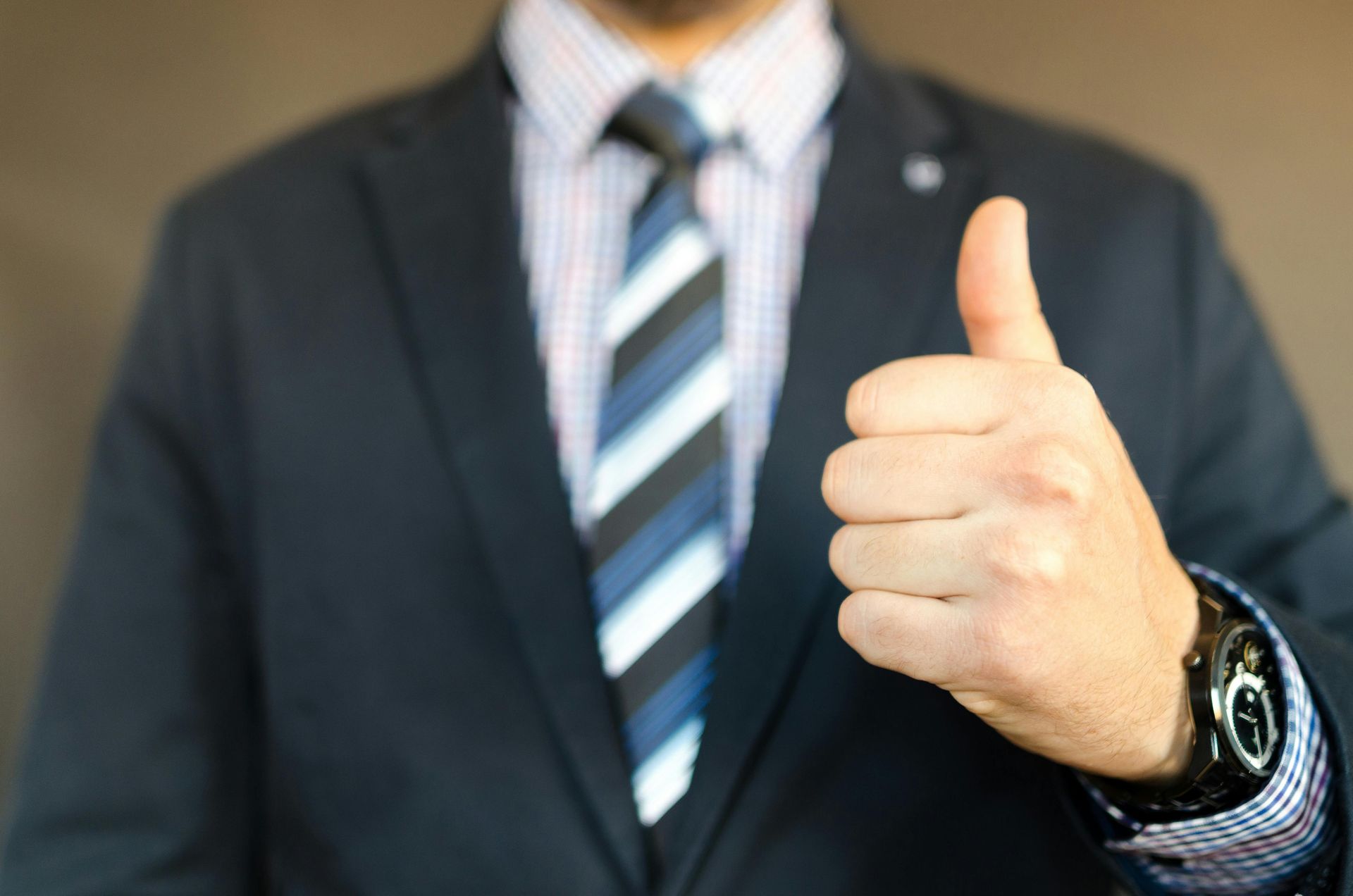A man in a suit and tie is giving a thumbs up.