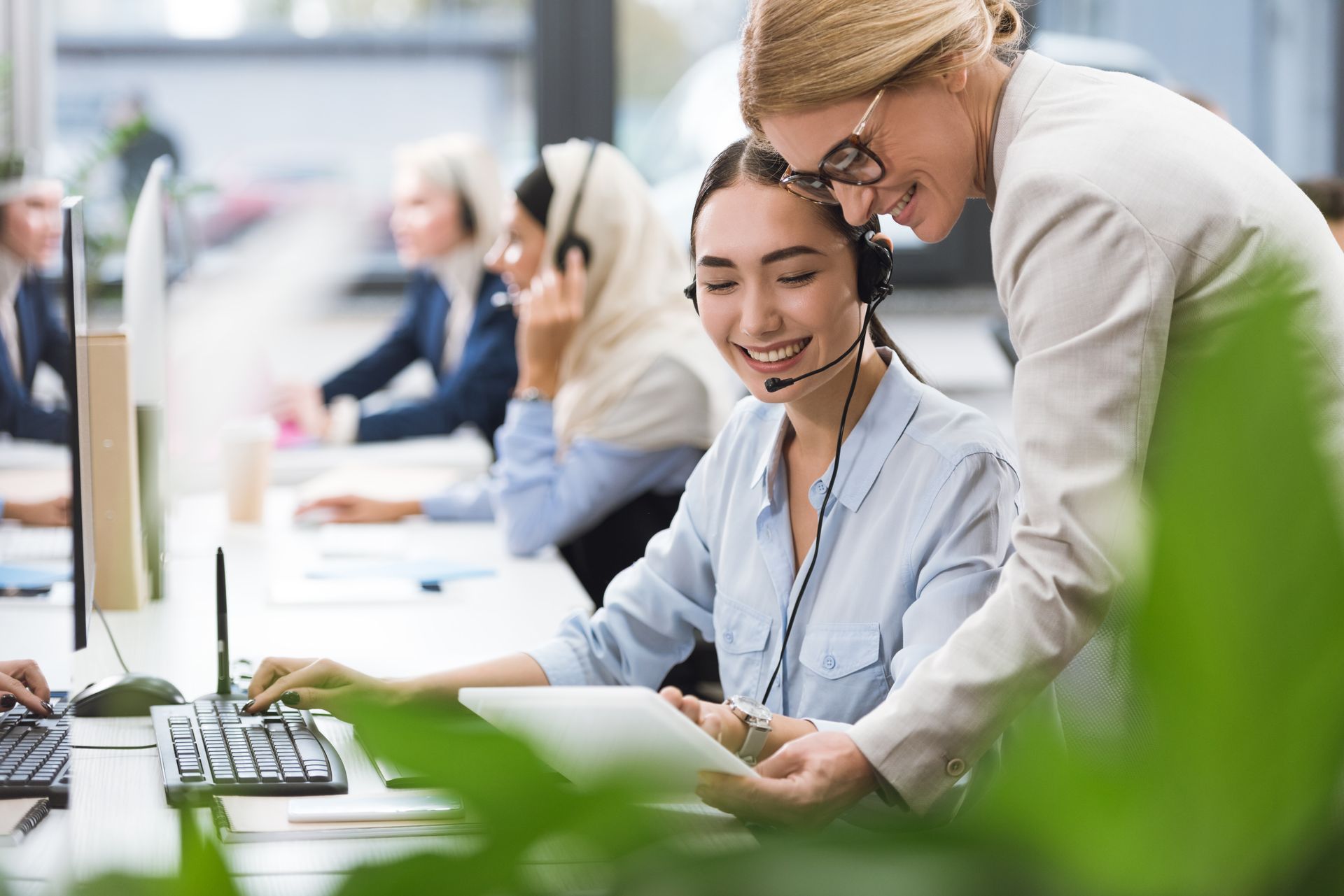 A woman is teaching another woman how to use a computer.