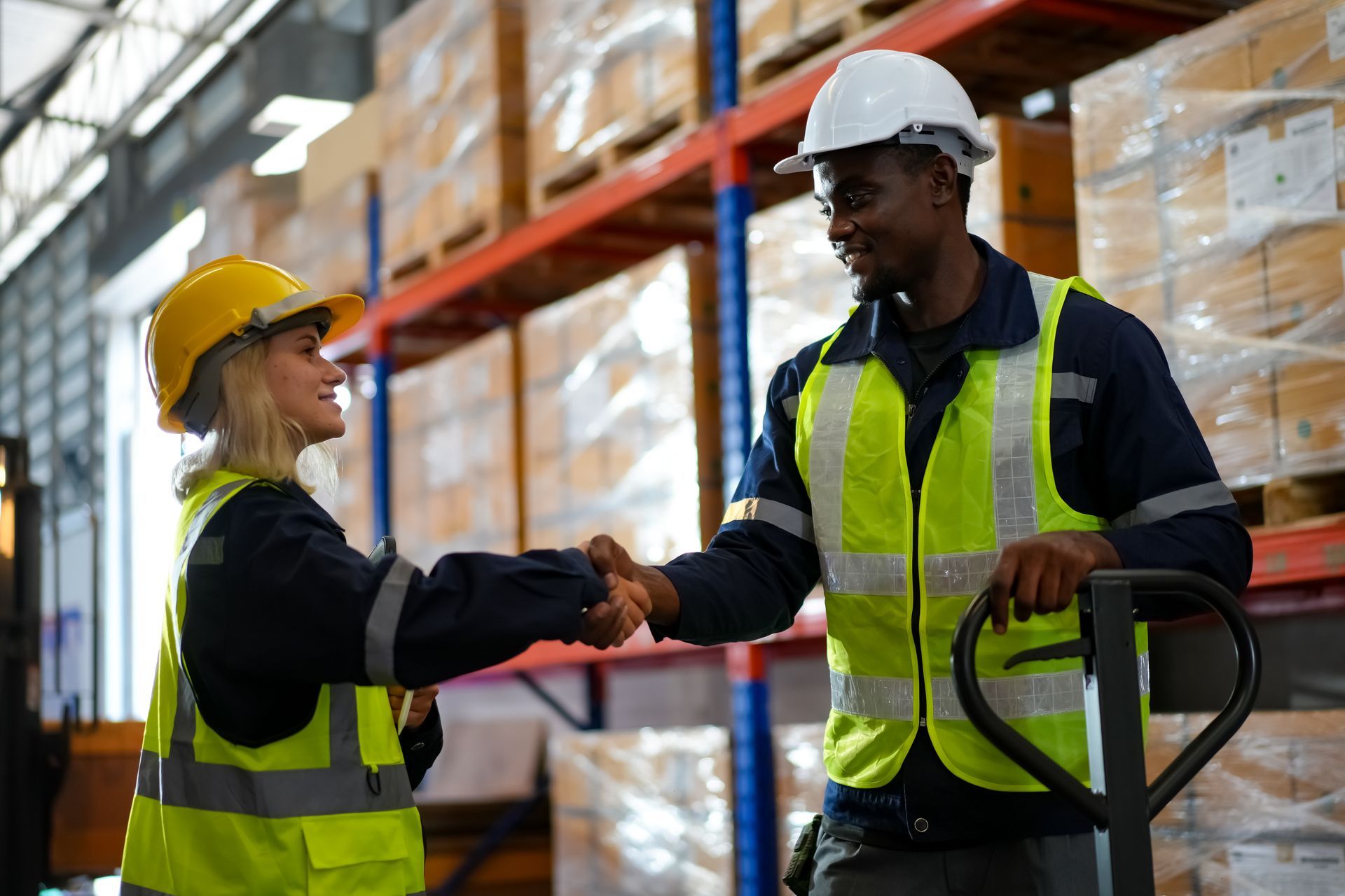 A man and a woman are shaking hands in a warehouse.