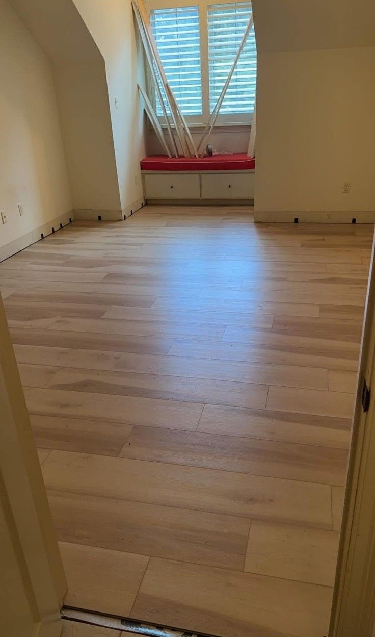 Empty room with light wood floor, window blinds, and a red radiator beneath the window.