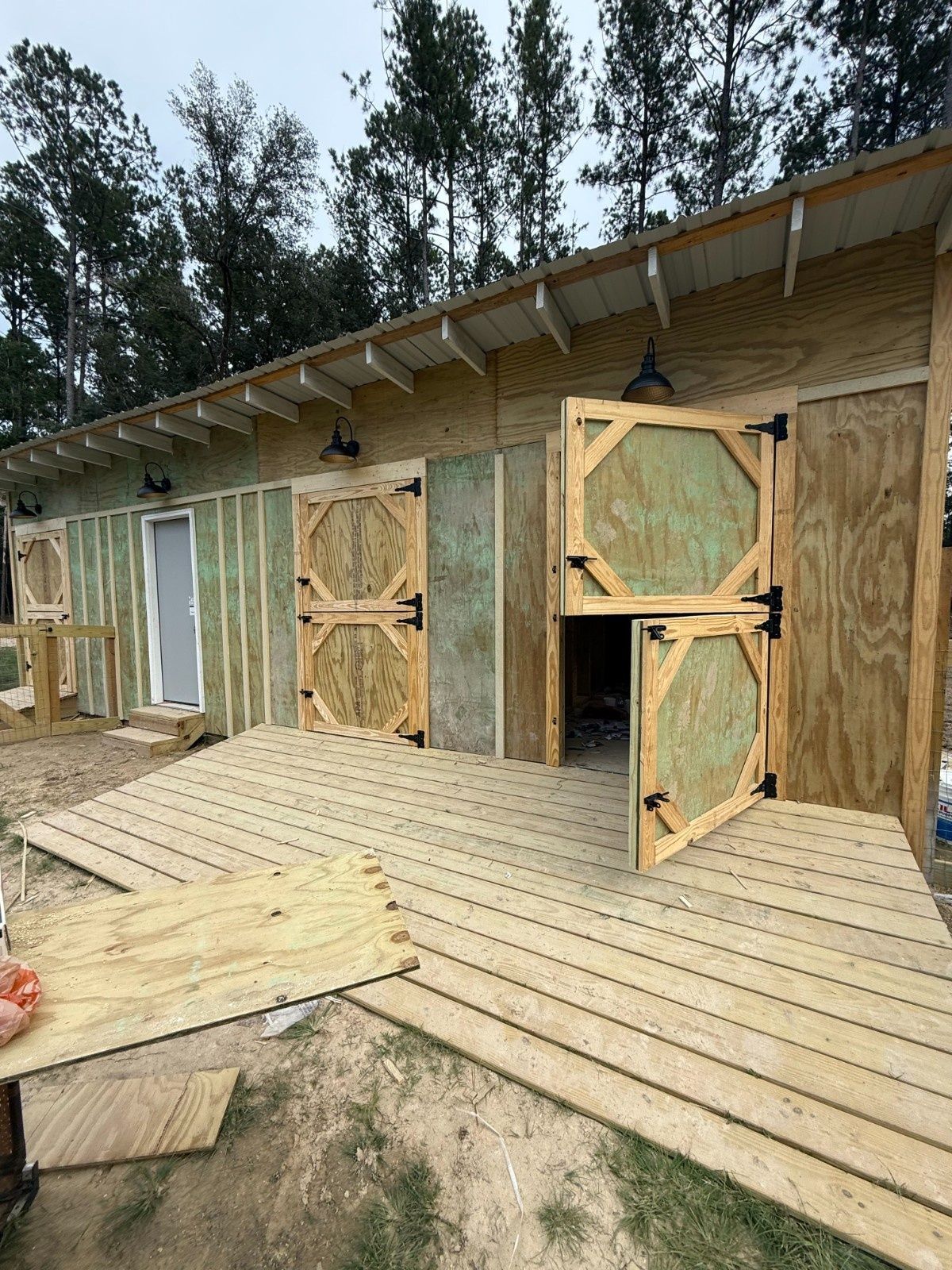Wooden cabin exterior with open Dutch doors and a slatted porch under construction