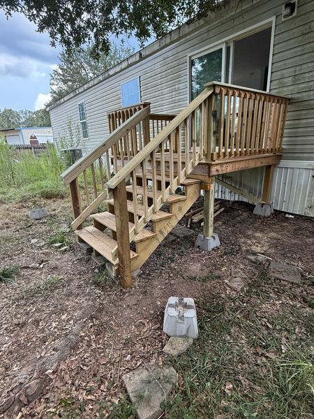 Wooden stairs and small ramp leading to a house entrance, with cinder blocks on the ground below.