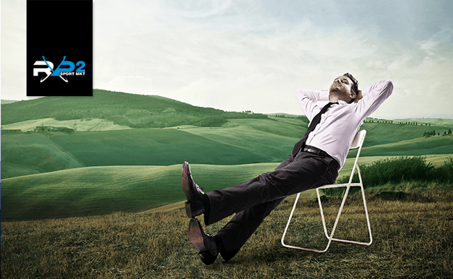 Homem em traje de negócios relaxando em uma cadeira ao ar livre com colinas verdes.