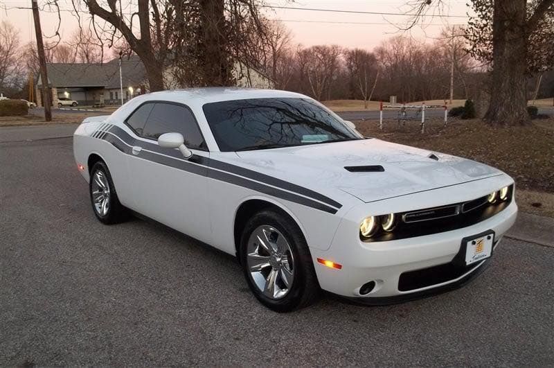 A white dodge challenger is parked on the side of the road