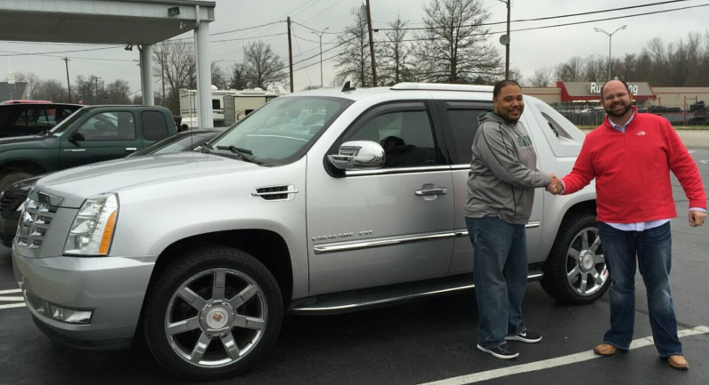 Two men shaking hands in front of a silver suv
