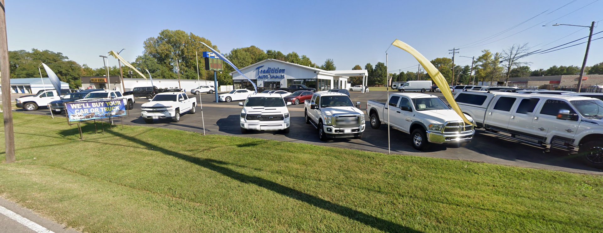 A lot of cars are parked in front of a car dealership.