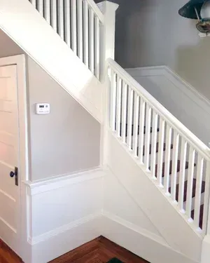 White staircase with wooden steps and railing in a home. The wall is light gray.