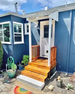 Blue house with wooden porch steps, white door, and small wooden railing.