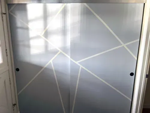 Sliding closet doors with a geometric white design on a gray background.