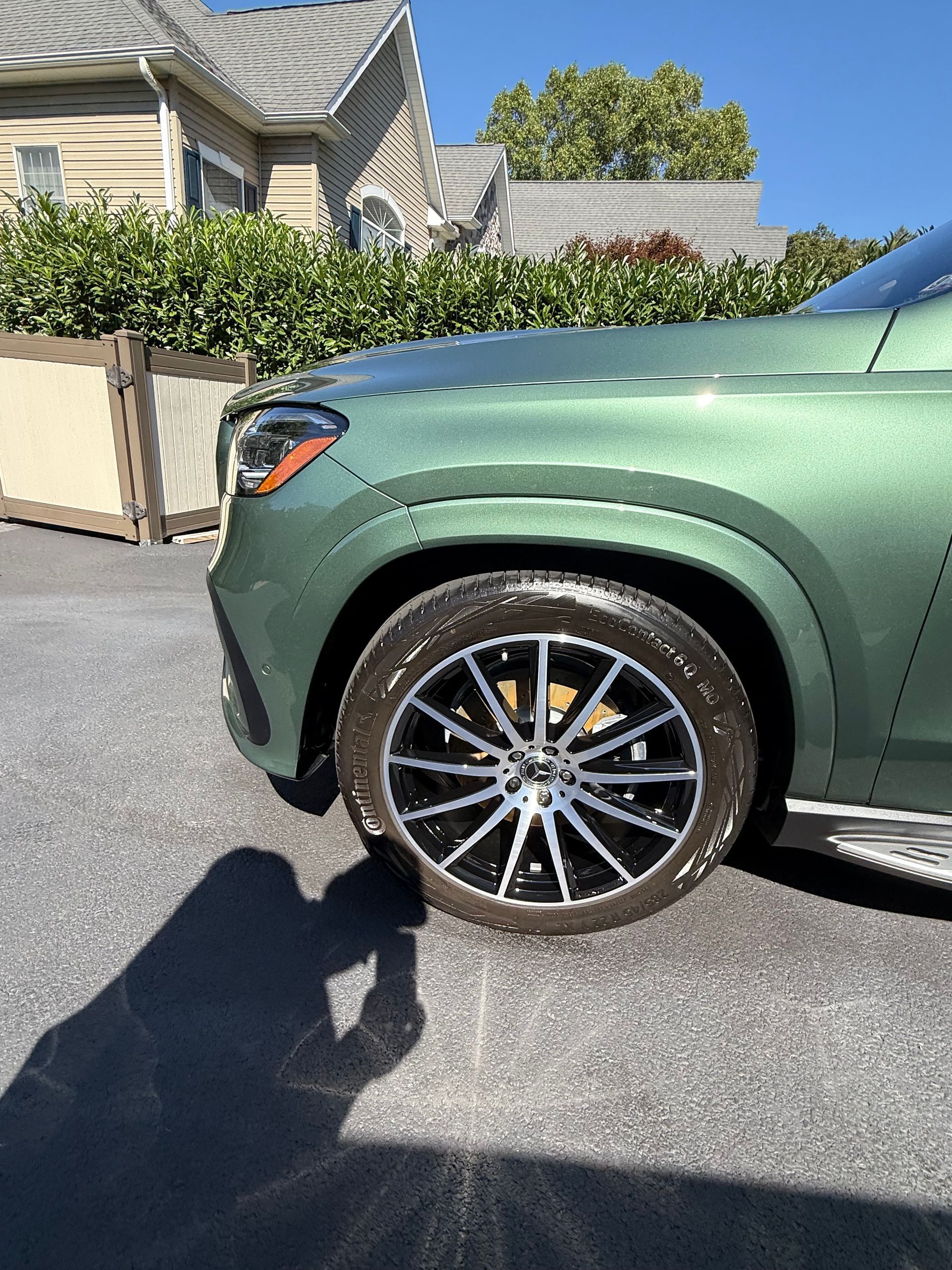 Green Mercedes SUV front wheel and fender, sunny outdoor setting.
