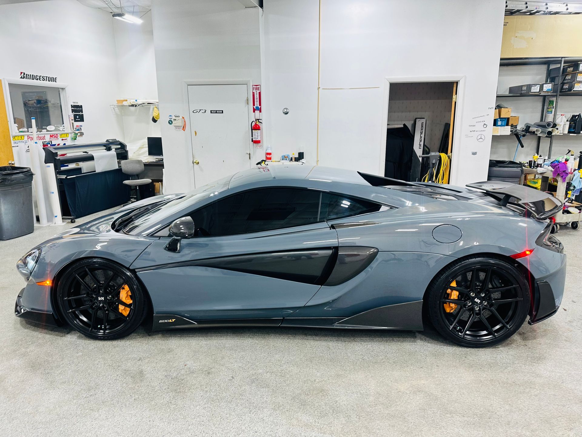 A gray sports car is parked in a garage.