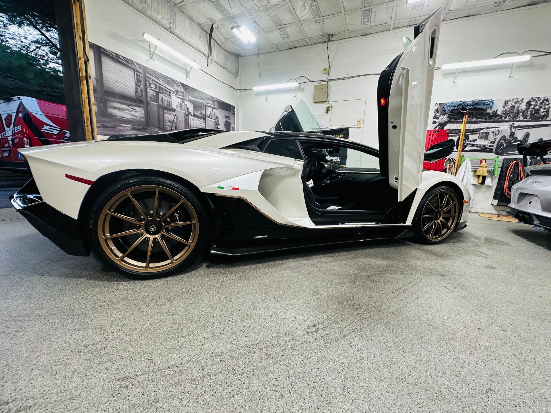 A white lamborghini aventador is parked in a garage with its doors open.