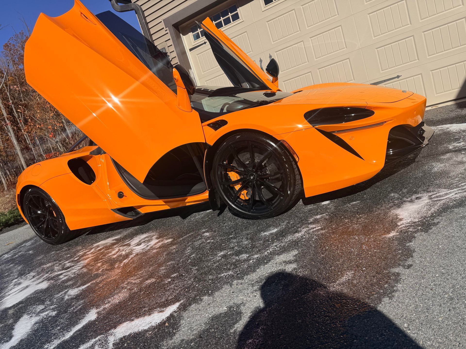 A bright red sports car parked in front of a red and white branded auto detailing van on an asphalt lot.