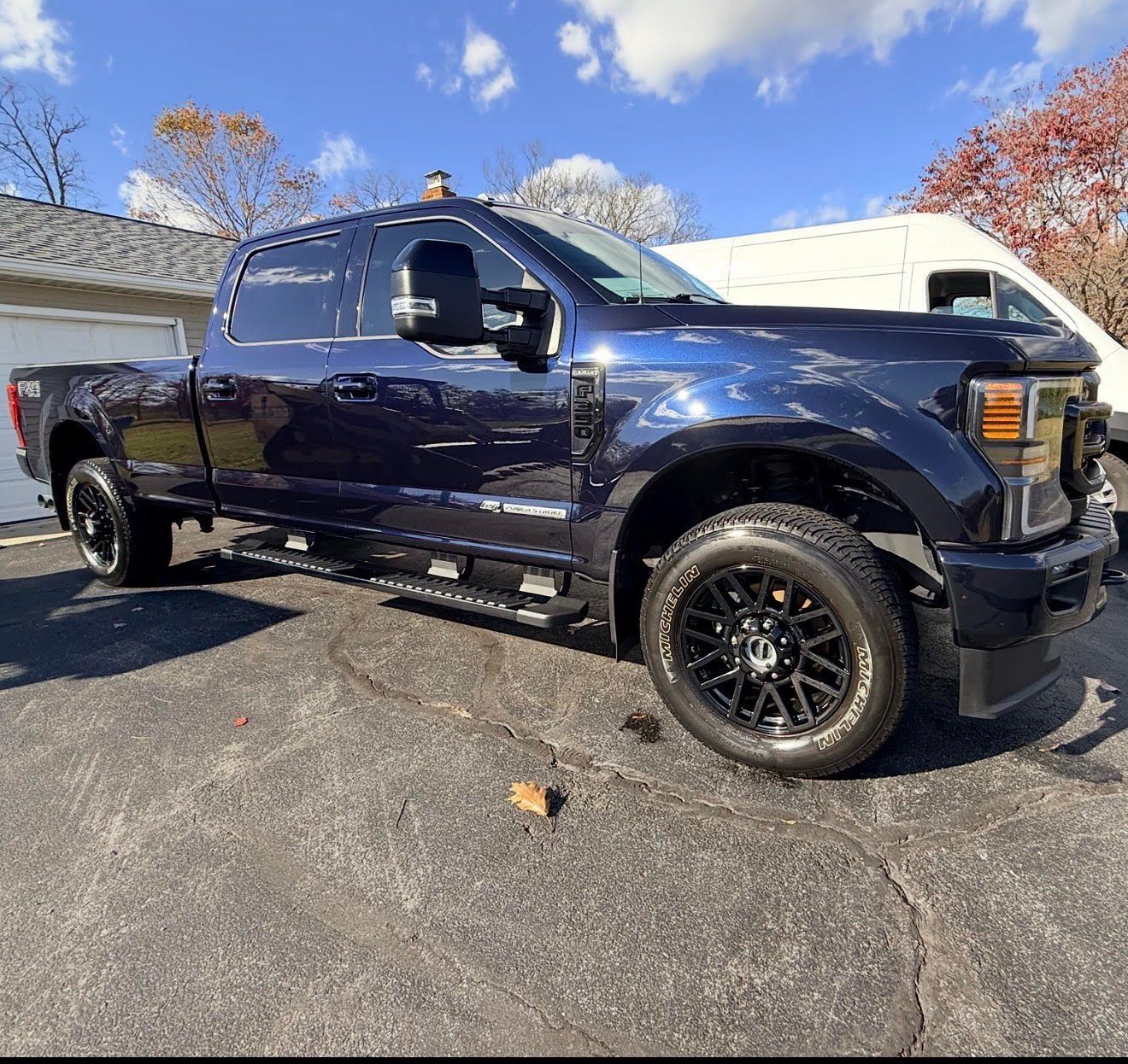 Dark blue Ford pickup truck parked on asphalt driveway. Cloudy sky in the background.