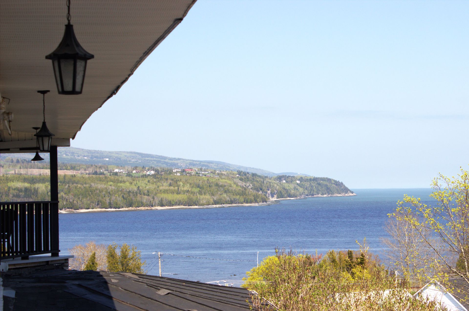 Balcony overlooking a blue bay and green coastline under a clear sky
