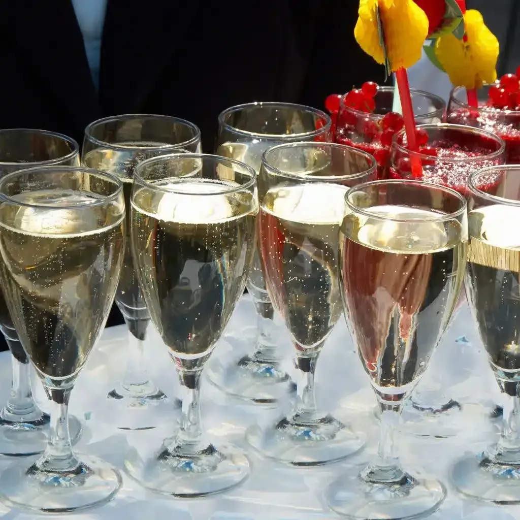 Champagne glasses on a tray with ice, red and yellow flowers in the background